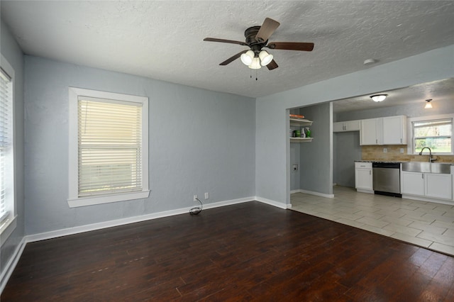 unfurnished living room featuring sink, hardwood / wood-style floors, a textured ceiling, and ceiling fan