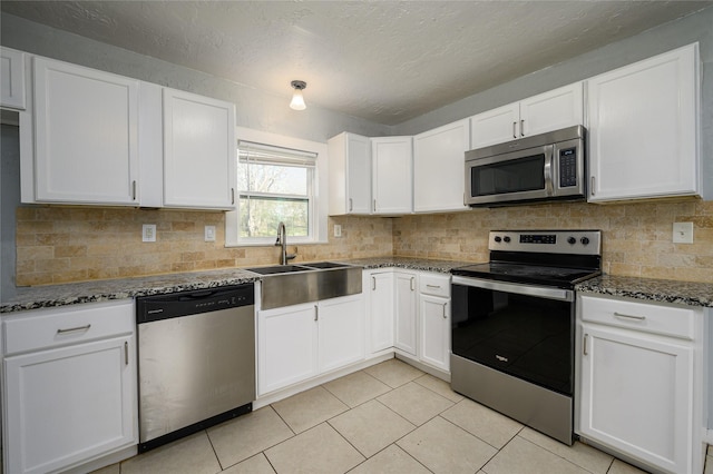 kitchen featuring white cabinetry, stainless steel appliances, and dark stone countertops