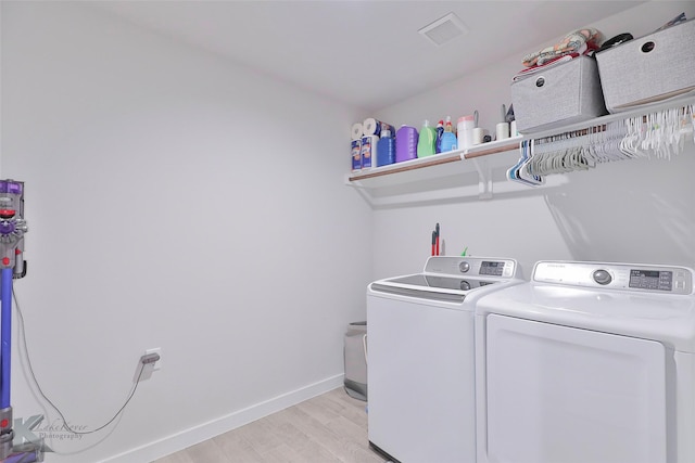 laundry area with washer and clothes dryer and light hardwood / wood-style flooring