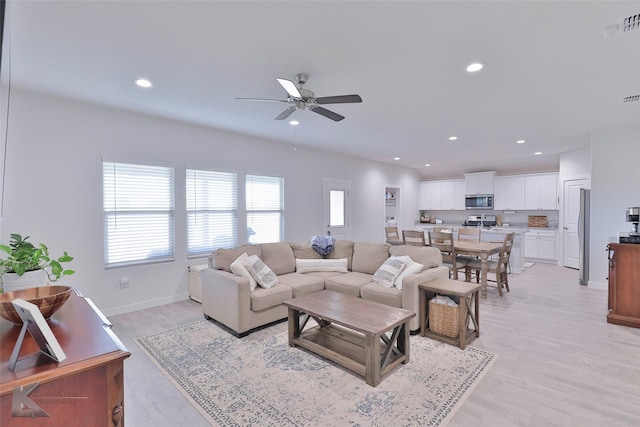 living room featuring ceiling fan and light hardwood / wood-style floors