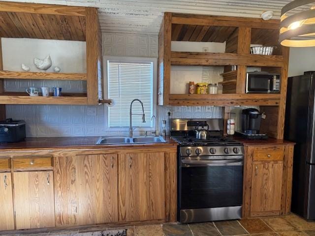 kitchen featuring black fridge, sink, gas stove, and backsplash