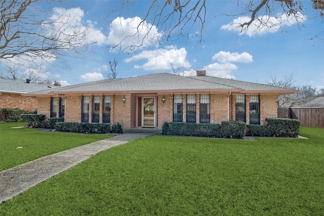 ranch-style house with a shingled roof, brick siding, fence, a front lawn, and a chimney