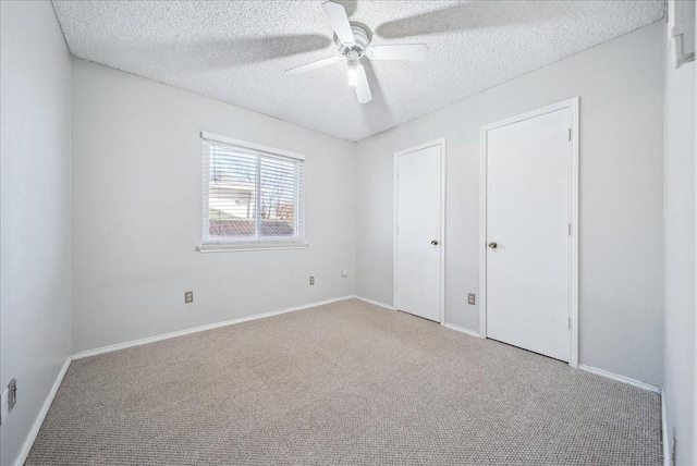 unfurnished bedroom featuring ceiling fan, light carpet, and a textured ceiling