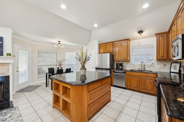 kitchen featuring light tile patterned flooring, a kitchen island, sink, a high end fireplace, and stainless steel appliances