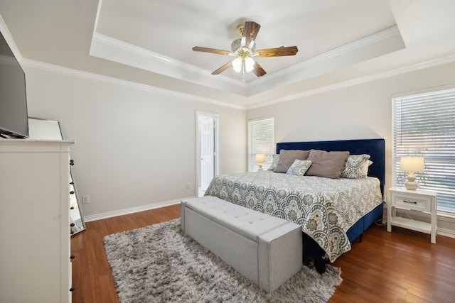 bedroom featuring dark wood-type flooring, ornamental molding, and a tray ceiling