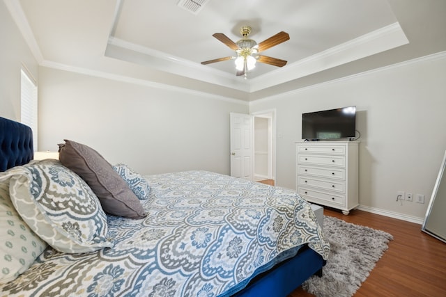 bedroom featuring dark hardwood / wood-style floors, ornamental molding, a raised ceiling, and ceiling fan