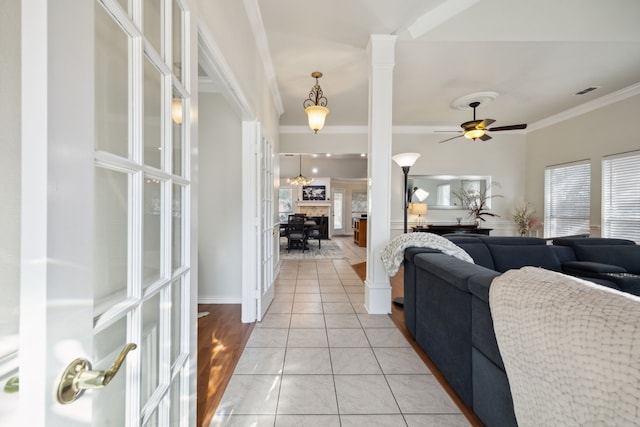 tiled living room featuring decorative columns, crown molding, and ceiling fan