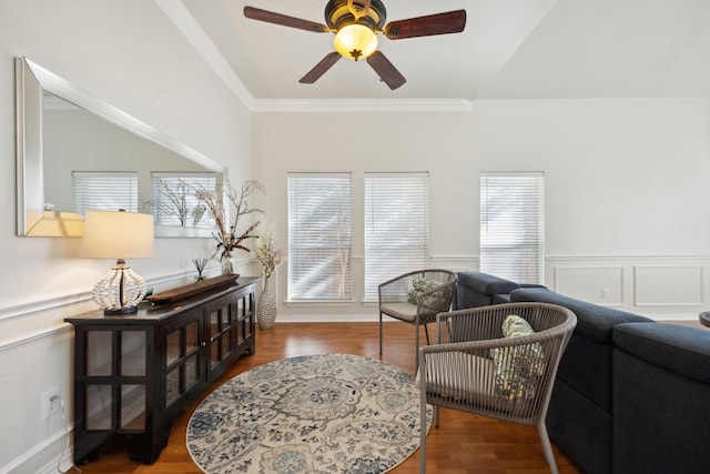 living area with dark wood-type flooring, ceiling fan, and crown molding