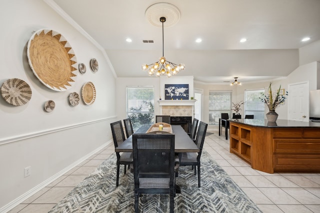 tiled dining room with an inviting chandelier, crown molding, and a tiled fireplace