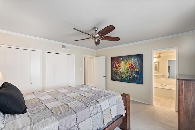 bedroom featuring crown molding, light colored carpet, connected bathroom, and two closets