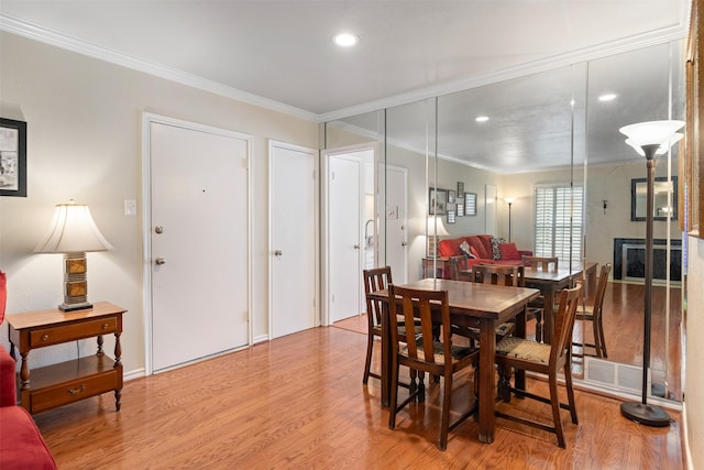 dining room with crown molding and light wood-type flooring