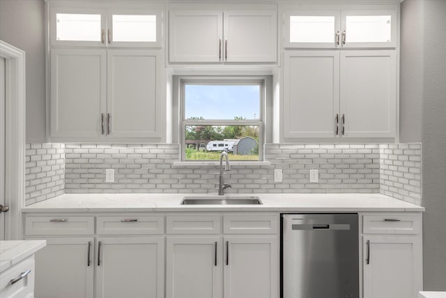 kitchen featuring sink, dishwasher, white cabinetry, light stone countertops, and decorative backsplash