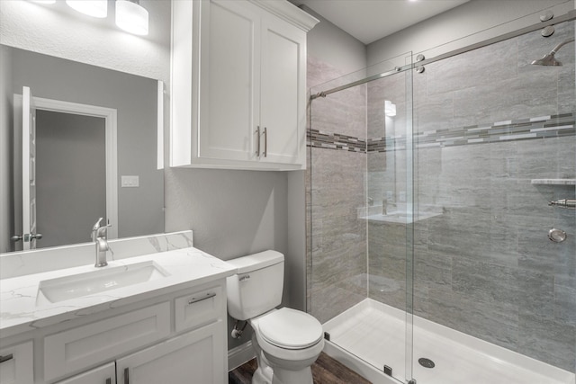 bathroom featuring toilet, vanity, and a shower with shower door