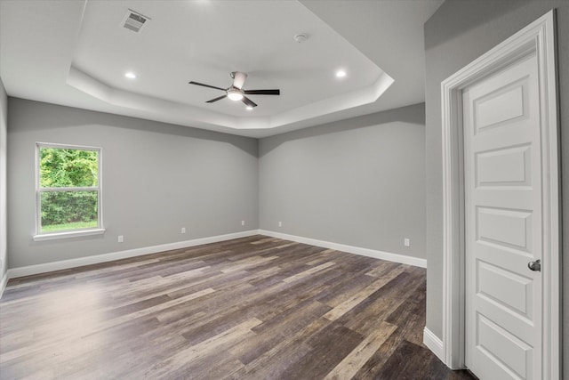 spare room with ceiling fan, dark hardwood / wood-style flooring, and a tray ceiling