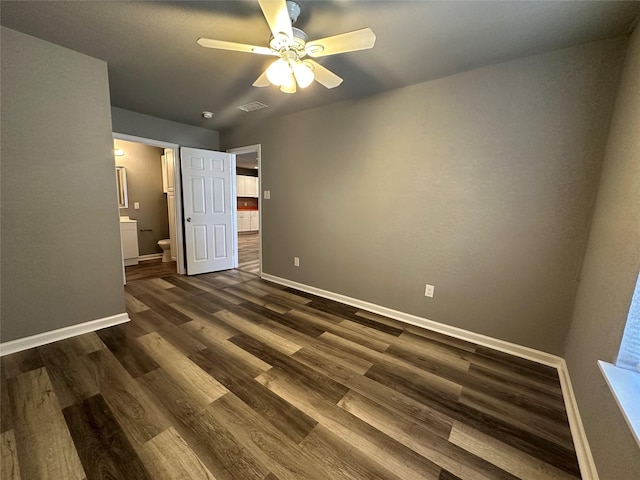 unfurnished bedroom featuring connected bathroom, dark wood-type flooring, and ceiling fan