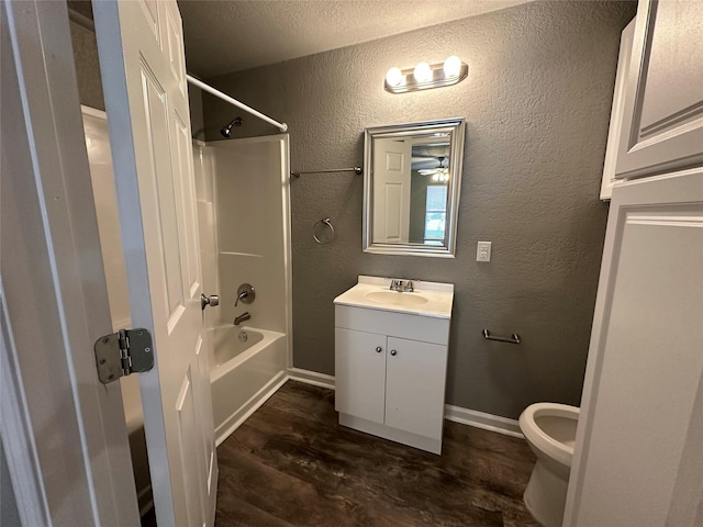 full bathroom featuring hardwood / wood-style flooring, shower / bath combination, vanity, a textured ceiling, and toilet