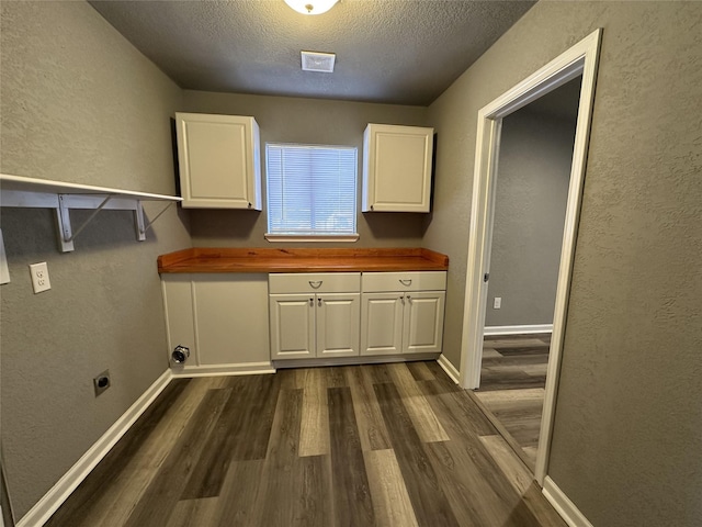 laundry area with electric dryer hookup, dark wood-type flooring, cabinets, and a textured ceiling