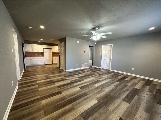 unfurnished living room with dark wood-type flooring, ceiling fan, and a textured ceiling