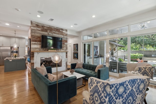 living room with a large fireplace and light hardwood / wood-style flooring