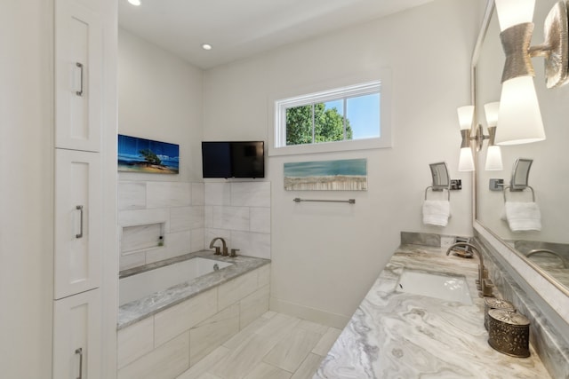 bathroom featuring a relaxing tiled tub and vanity