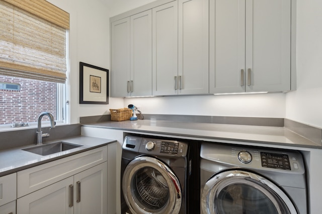 clothes washing area featuring cabinets, sink, and independent washer and dryer