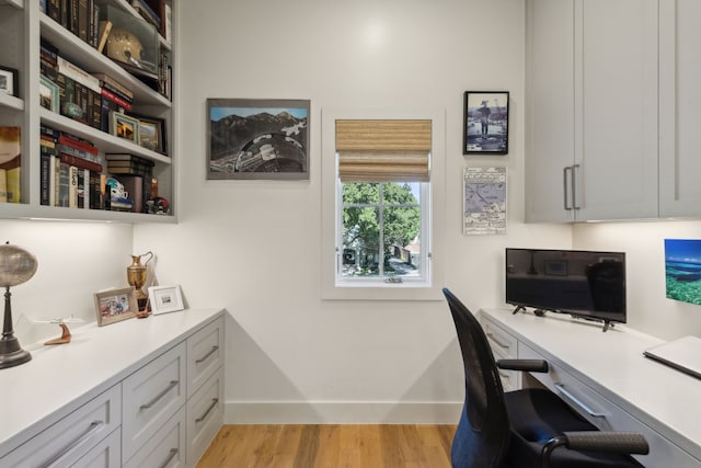 office with built in desk and light hardwood / wood-style flooring