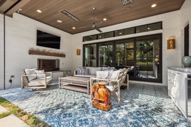 view of patio / terrace with ceiling fan and an outdoor living space with a fireplace