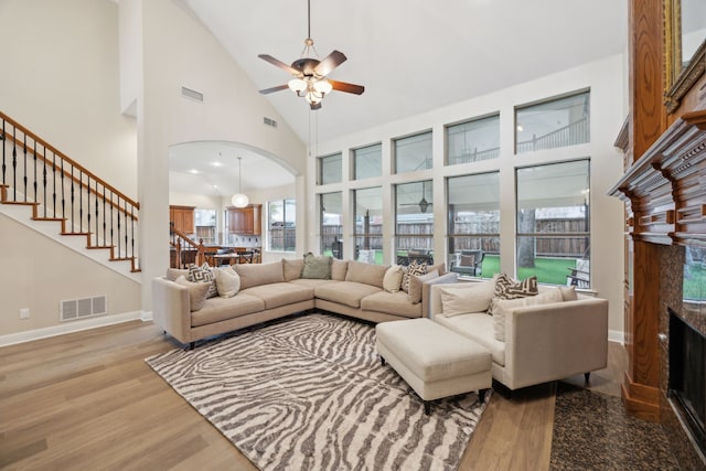 living room featuring ceiling fan, high vaulted ceiling, and light hardwood / wood-style flooring