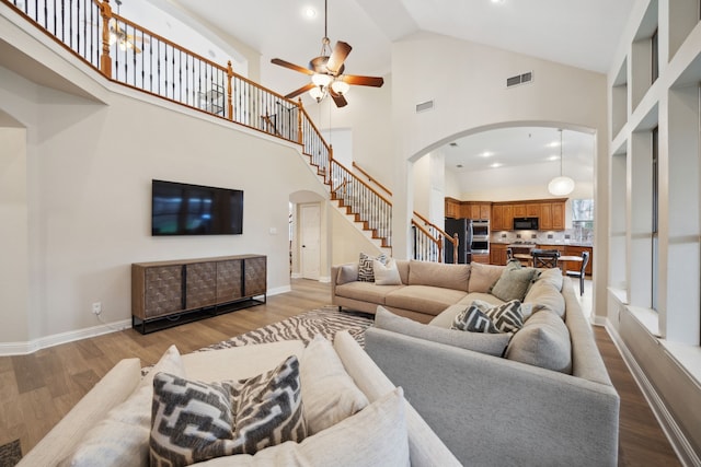 living room with ceiling fan, high vaulted ceiling, and light wood-type flooring