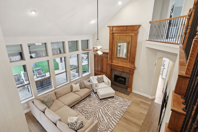 living room featuring ceiling fan, high vaulted ceiling, a high end fireplace, and light hardwood / wood-style flooring