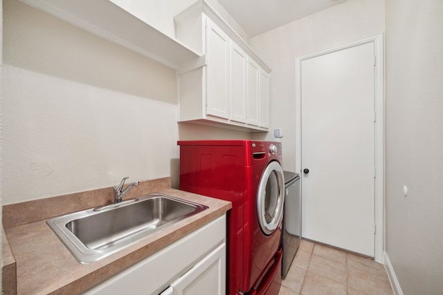 clothes washing area featuring light tile patterned flooring, cabinets, washer and clothes dryer, and sink