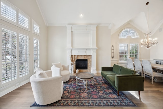 living room featuring hardwood / wood-style flooring, high vaulted ceiling, ornamental molding, a large fireplace, and a chandelier