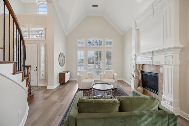 living room with high vaulted ceiling, a high end fireplace, and light hardwood / wood-style floors