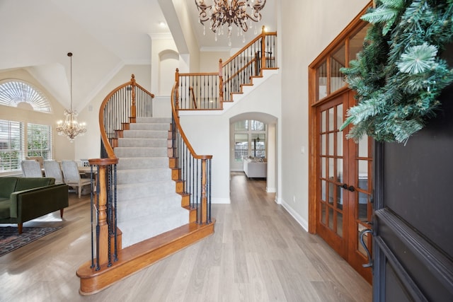 entryway featuring high vaulted ceiling, light wood-type flooring, and a chandelier