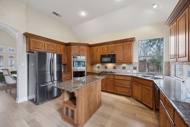 kitchen with lofted ceiling, a center island, dark stone countertops, and black appliances