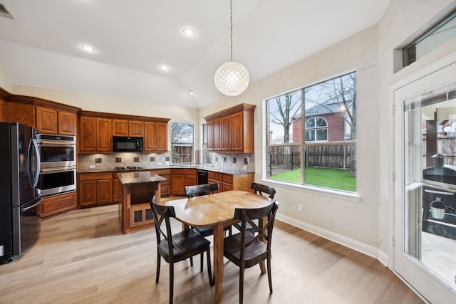 kitchen with pendant lighting, backsplash, black appliances, and a center island