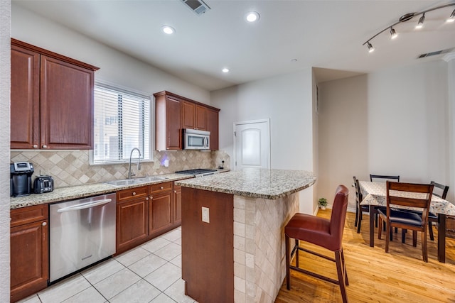 kitchen with appliances with stainless steel finishes, tasteful backsplash, sink, a breakfast bar area, and a center island