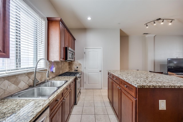 kitchen featuring tasteful backsplash, sink, a center island, light tile patterned floors, and stainless steel appliances