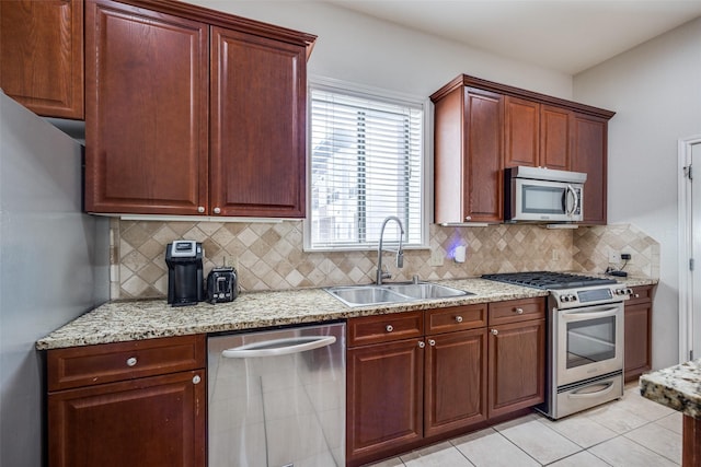 kitchen with light stone counters, sink, backsplash, and appliances with stainless steel finishes