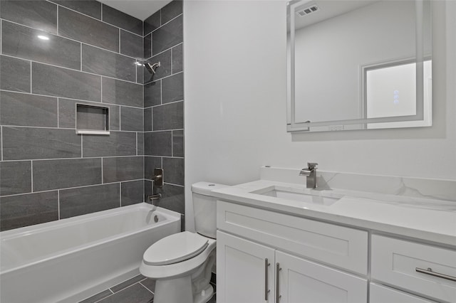 full bathroom featuring tile patterned flooring, tiled shower / bath, vanity, and toilet