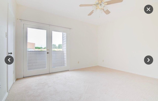 carpeted spare room with ceiling fan and french doors