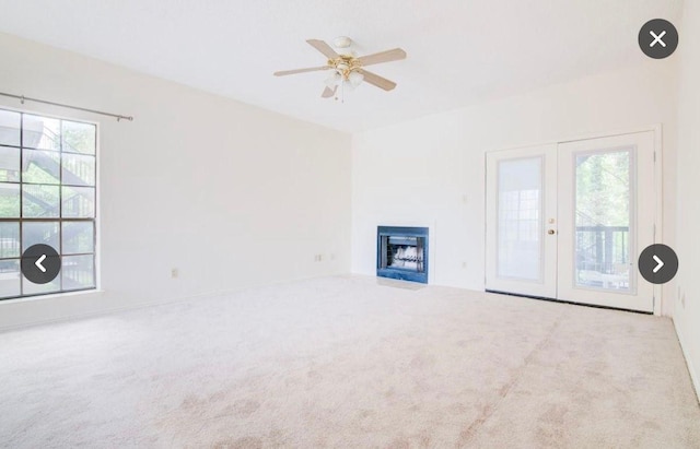 unfurnished living room featuring a wealth of natural light, french doors, ceiling fan, and carpet flooring