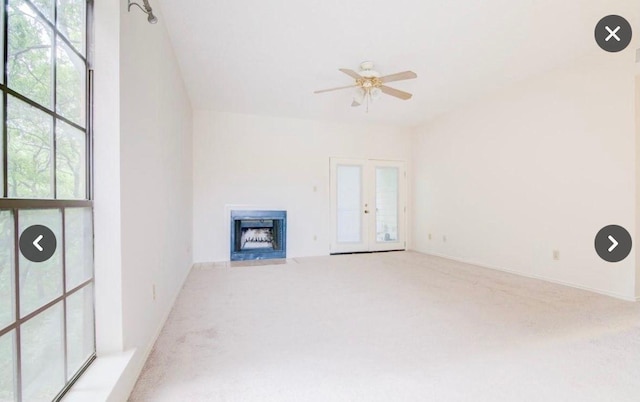 unfurnished living room with a fireplace with flush hearth, carpet floors, and a ceiling fan