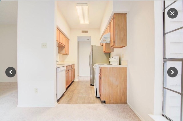 kitchen with stove, light colored carpet, light brown cabinetry, and white dishwasher