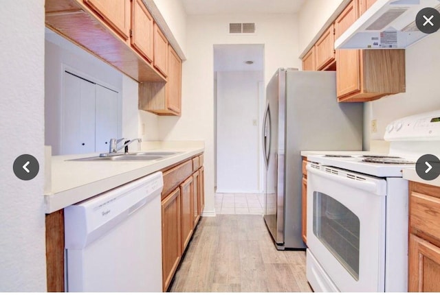 kitchen with sink, light brown cabinetry, white appliances, and light hardwood / wood-style floors