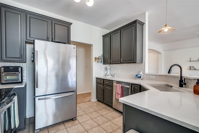 kitchen with appliances with stainless steel finishes, pendant lighting, sink, backsplash, and light tile patterned floors