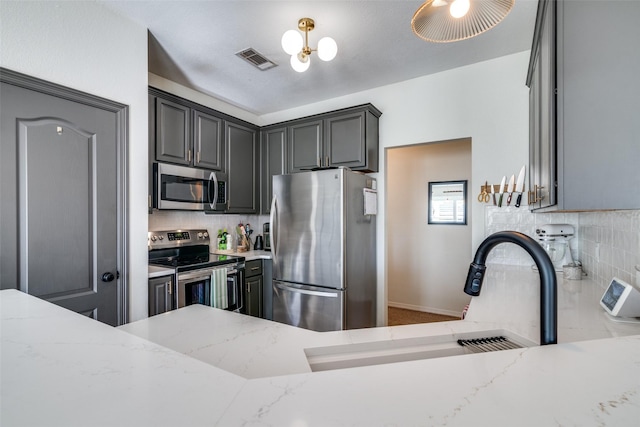 kitchen with gray cabinets, light stone countertops, appliances with stainless steel finishes, and sink