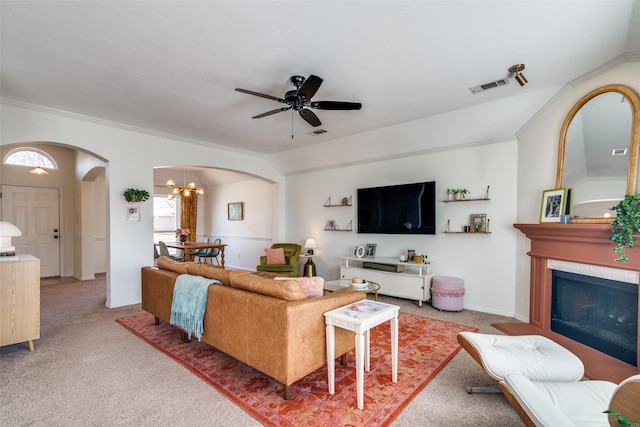 living room featuring ceiling fan with notable chandelier, ornamental molding, lofted ceiling, and carpet floors