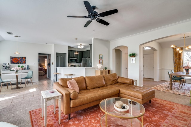 tiled living room with ornamental molding, lofted ceiling, and ceiling fan with notable chandelier