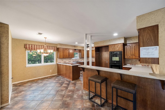 kitchen with a kitchen breakfast bar, backsplash, double oven, and kitchen peninsula